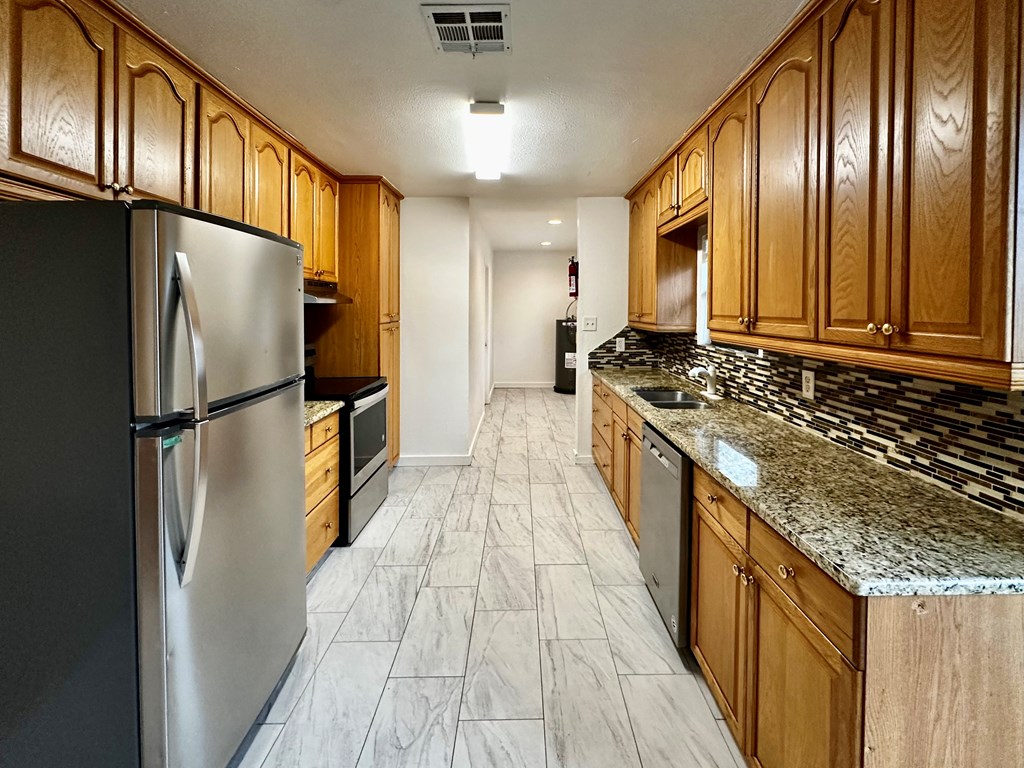 711 Center Street Kerrville, TX 78028 - Photo 4 of 9 a kitchen with granite countertop stainless steel appliances a refrigerator stove top oven and cabinets
