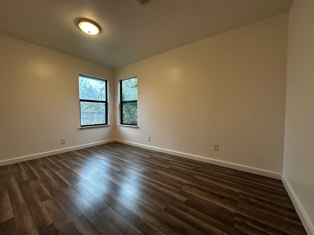 711 Center Street Kerrville, TX 78028 - Photo 7 of 9 an empty room with wooden floor and windows