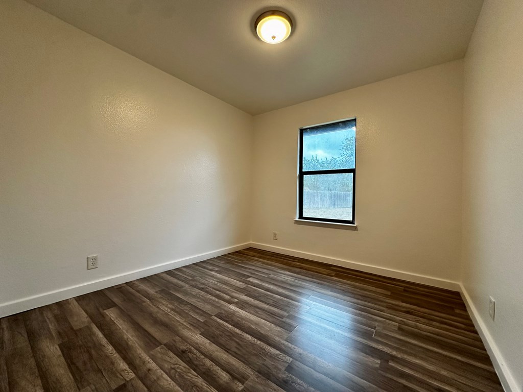 711 Center Street Kerrville, TX 78028 - Photo 8 of 9 an empty room with wooden floor and windows