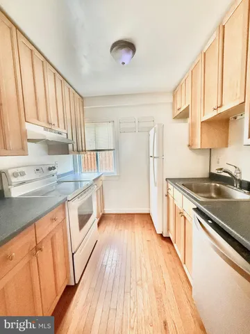 a kitchen with granite countertop wooden floors and white stainless steel appliances