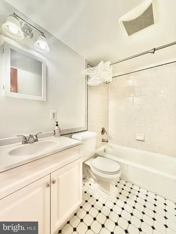 a bathroom with a granite countertop sink a toilet a mirror a bathtub and shower