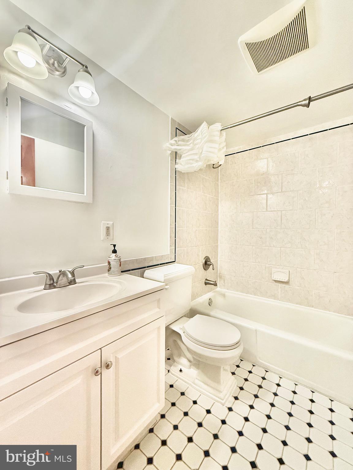 720 West Glebe Road, Unit 2A Alexandria, VA 22305 - Photo 4 of 15 a bathroom with a granite countertop sink a toilet a mirror a bathtub and shower