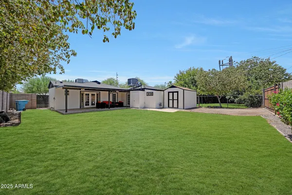 a view of a white house in front of a big yard with large trees
