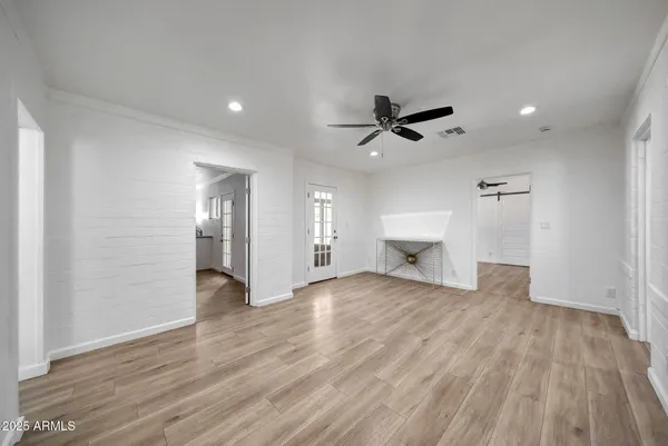 an empty room with wooden floor a ceiling fan a fireplace and windows
