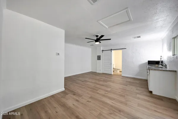 a view of empty room with wooden floor and fan