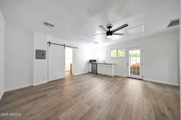 an empty room with wooden floor ceiling fan and windows