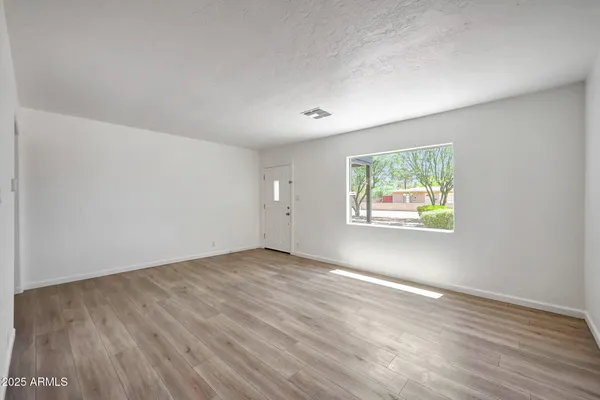 an empty room with wooden floor and windows