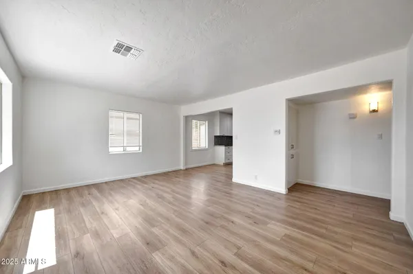 an empty room with wooden floor and windows