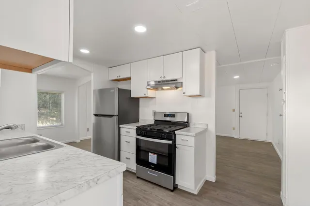 a kitchen with kitchen island white cabinets appliances and wooden floor
