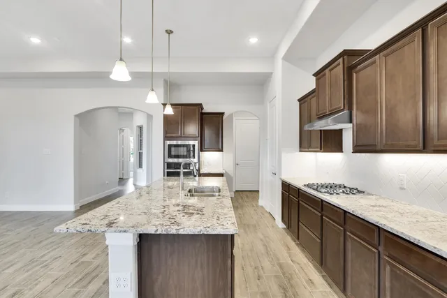a kitchen with stainless steel appliances granite countertop a sink refrigerator and cabinets