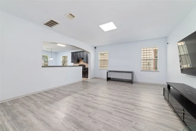 a view of an empty room with a window and wooden floor