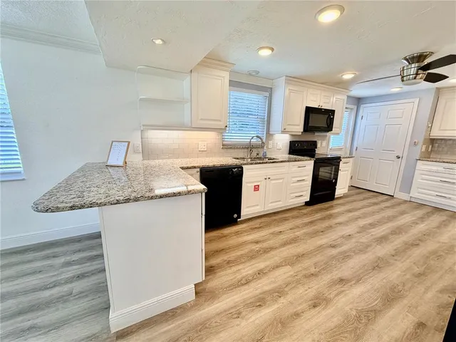a kitchen with stainless steel appliances kitchen island granite countertop a refrigerator and a sink