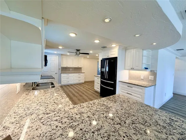 a kitchen with granite countertop a refrigerator and a sink