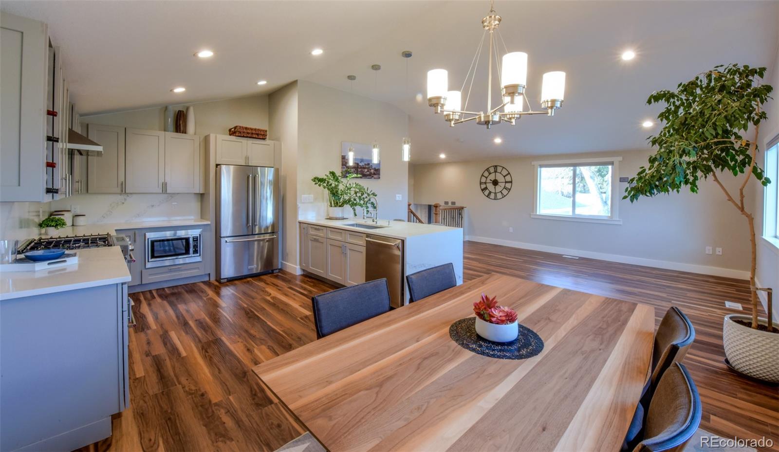 5389 West Roxbury Place Littleton, CO 80128 - Photo 5 of 31 a kitchen with stainless steel appliances granite countertop a refrigerator a sink dishwasher a stove a dining table and chairs with wooden floor
