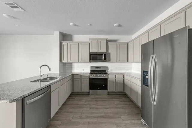 a kitchen with stainless steel appliances granite countertop a refrigerator sink and stove