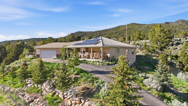 View of front of home featuring covered porch, roof mounted solar panels, driveway, a mountain view, and a garage