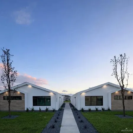 a front view of a house with a garden and a tree