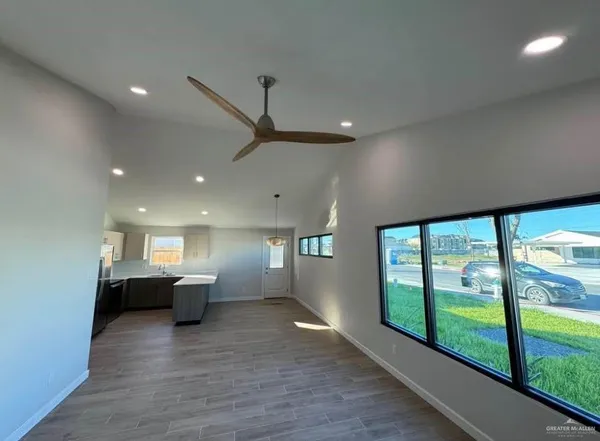 a view of empty room with wooden floor and fan