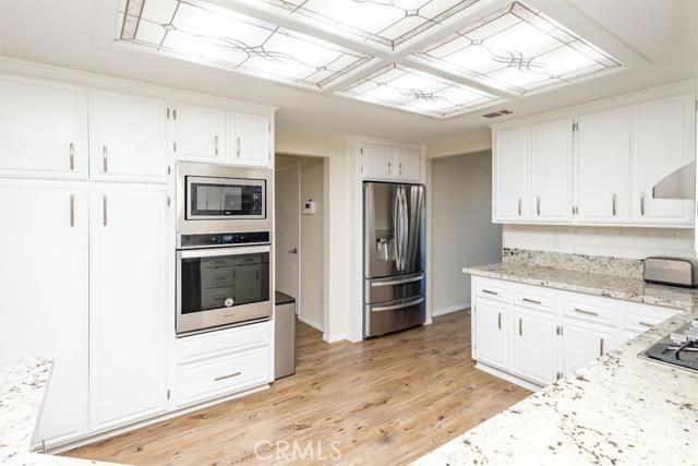 15222 Riverside Drive Apple Valley, CA 92307 - Photo 8 of 43 a kitchen with stainless steel appliances kitchen island granite countertop a refrigerator and a stove top oven