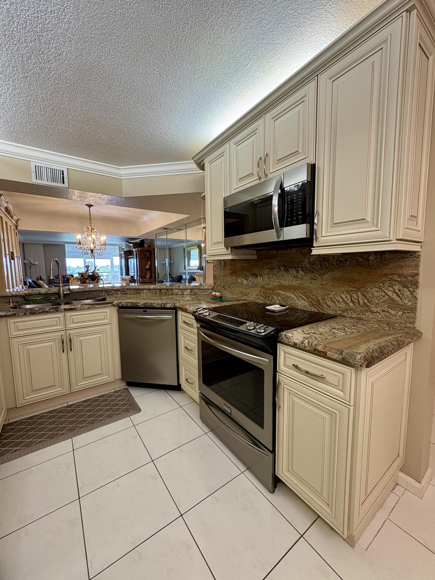 23249 Barwood Lane North, Unit 402 Boca Raton, FL 33428 - Photo 3 of 27 a kitchen with stainless steel appliances granite countertop a stove a sink and a microwave