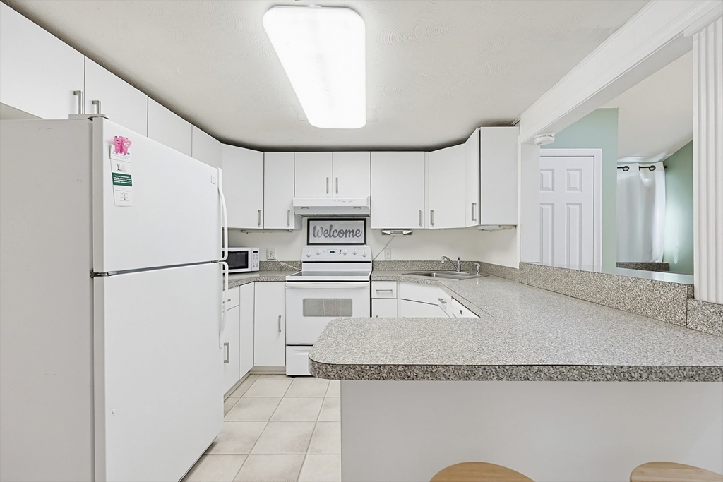 118 Spruce Road Norwood, MA 02062 - Photo 26 of 39 a white kitchen with granite countertop stainless steel appliances and a refrigerator