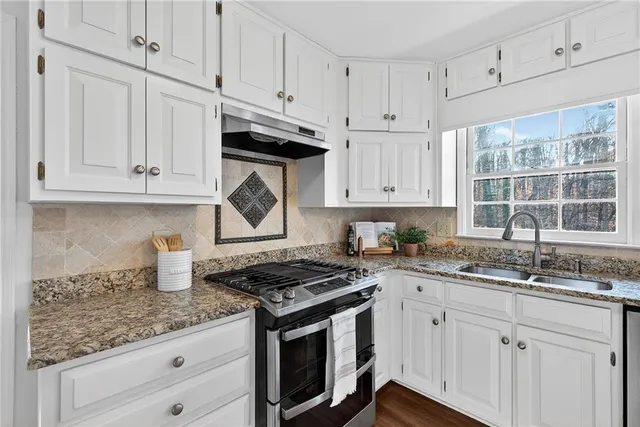 a kitchen with granite countertop white cabinets and a stove