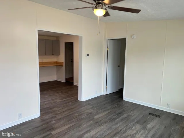 an empty room with wooden floor closet and windows