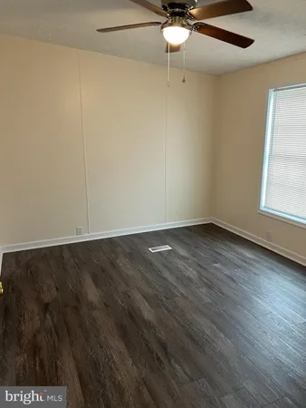 an empty room with a ceiling fan and window
