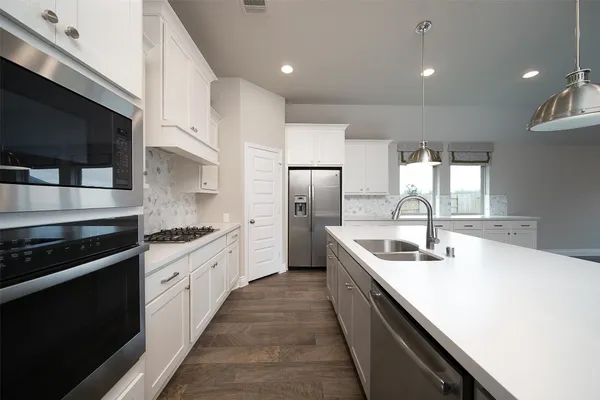 a kitchen with stainless steel appliances granite countertop a sink a stove and a refrigerator