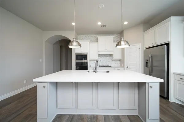 a large kitchen with a large counter top stainless steel appliances and cabinets