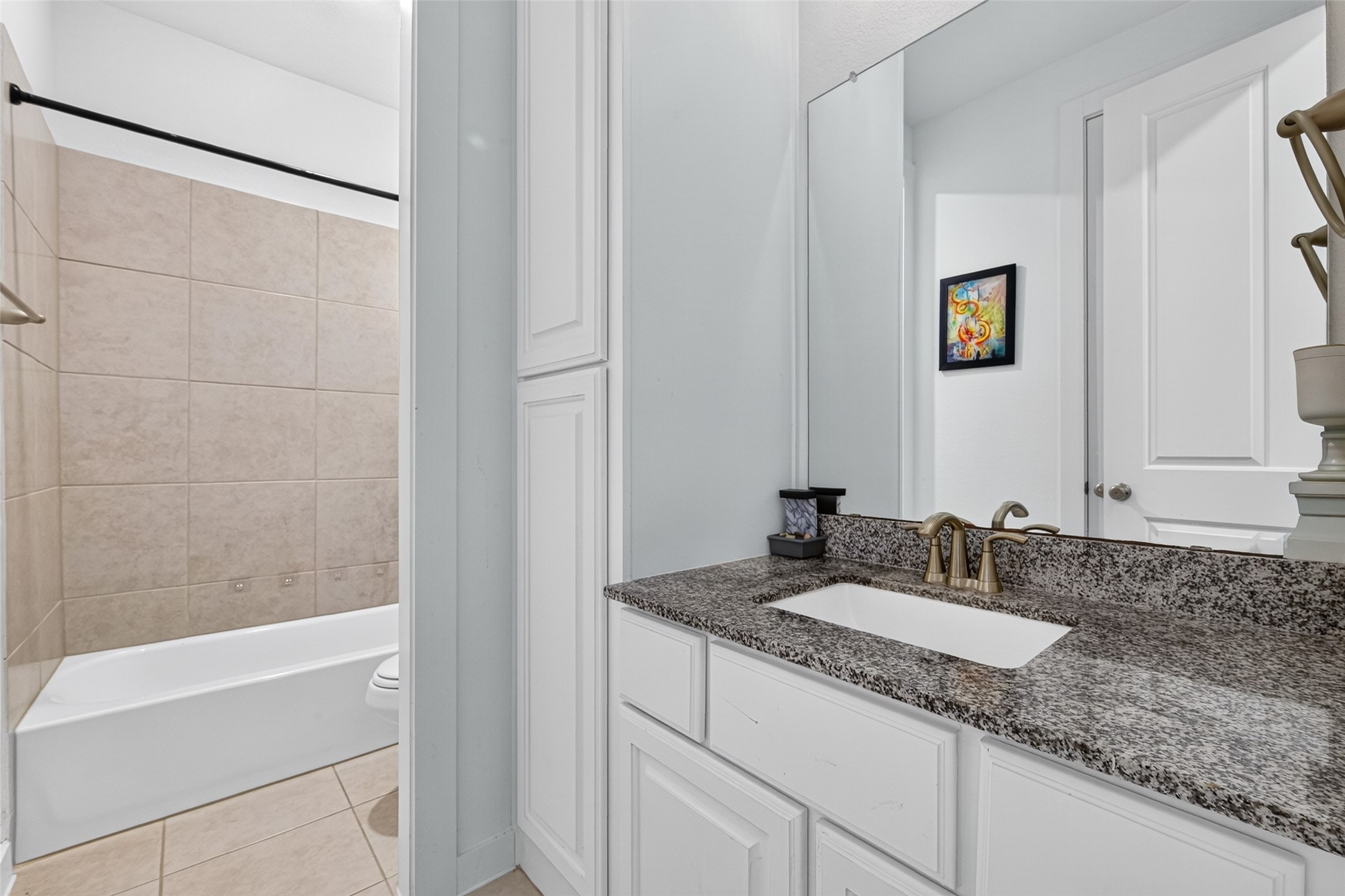 10114 Brush Way Rosharon, TX 77583 - Photo 42 of 50 Elegant bathroom featuring a granite countertop, sleek white cabinetry, and a tiled shower-tub combination for a modern touch.