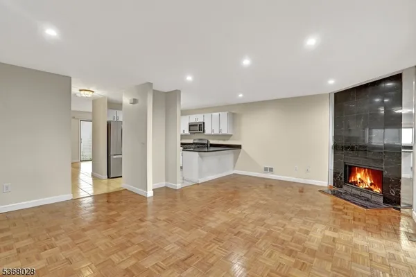 a view of an empty room with kitchen and a window