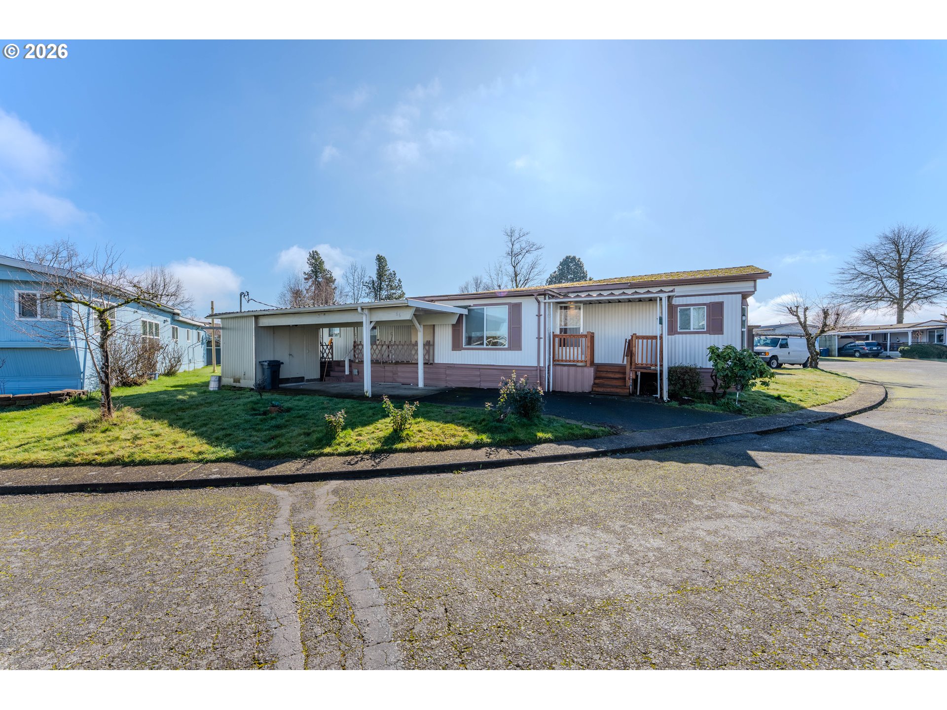 1999 Jansen Way, Unit 66 Woodburn, OR 97071 - Photo 2 of 26 a view of a white house next to a yard with big trees