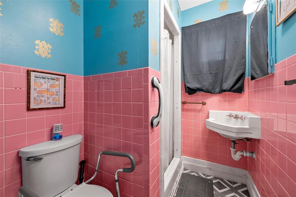 301 North 40th Street Waco, TX 76710 - Photo 16 of 26 Bathroom featuring pink wall tiling, a white wall-mounted sink, and a white toilet