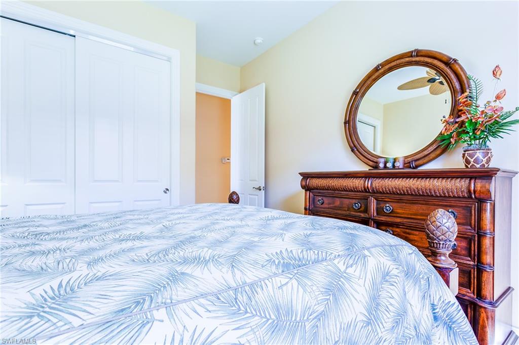 7747 Cottesmore Drive Naples, FL 34113 - Photo 19 of 32 a bedroom with a bed a mirror and a closet