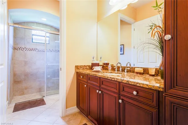 a bathroom with a granite countertop sink a mirror and a shower
