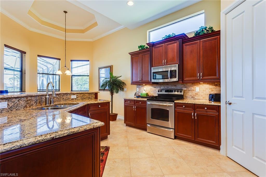 7747 Cottesmore Drive Naples, FL 34113 - Photo 10 of 32 a kitchen with stainless steel appliances granite countertop a sink a stove and a microwave
