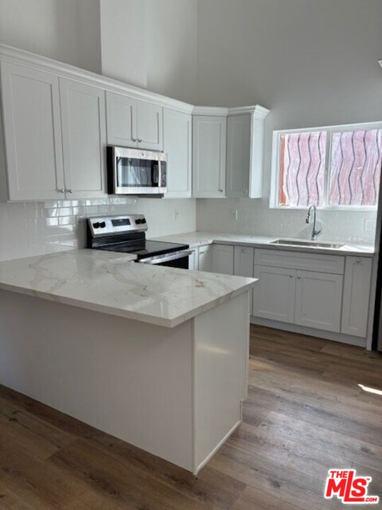 449 West 74th Street Los Angeles, CA 90003 - Photo 4 of 28 a kitchen with stainless steel appliances a sink a stove a microwave and wooden cabinets