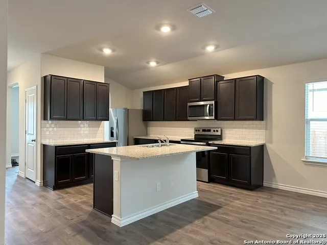 a kitchen with stainless steel appliances granite countertop a stove top oven a sink and a microwave