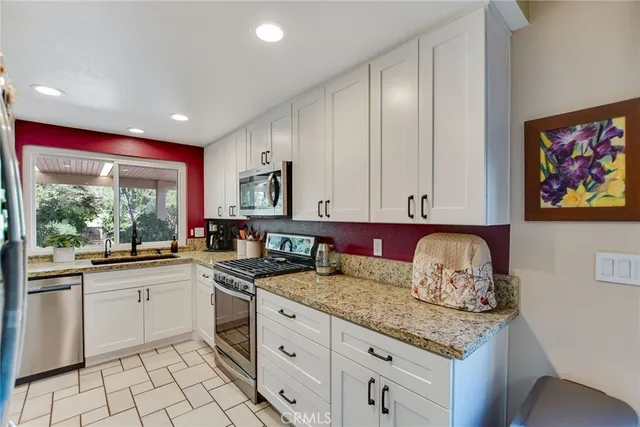 a kitchen with granite countertop white cabinets and window