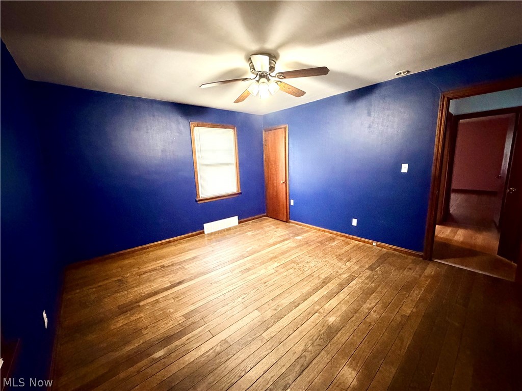 10506 Park Heights Road Cleveland, OH 44104 - Photo 15 of 22 Room with wood-finish flooring, a window with wood trim, and a ceiling fan with integrated lighting