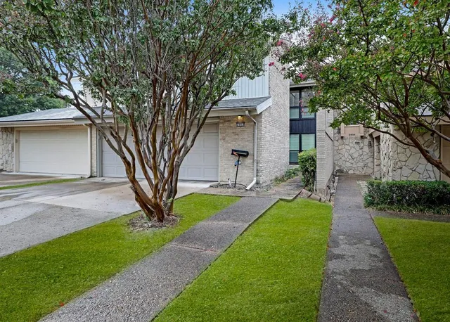 a front view of a house with a garden and tree