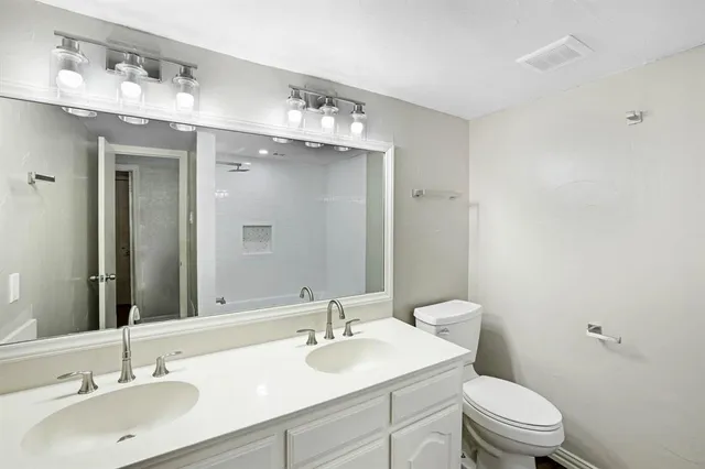 a bathroom with a granite countertop sink a toilet and a mirror