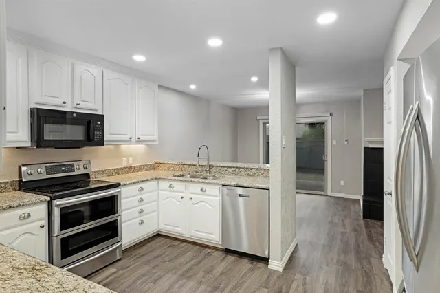 a view of an empty room with wooden floor fireplace and a window
