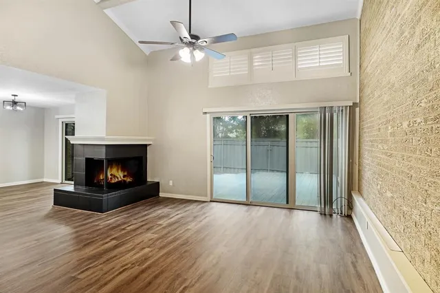 a view of an empty room with wooden floor fireplace and a window