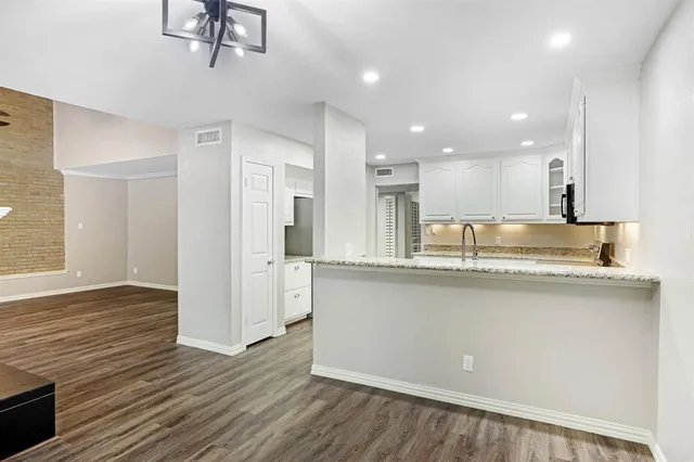 a large kitchen with stainless steel appliances granite countertop a large counter top and a wooden floor