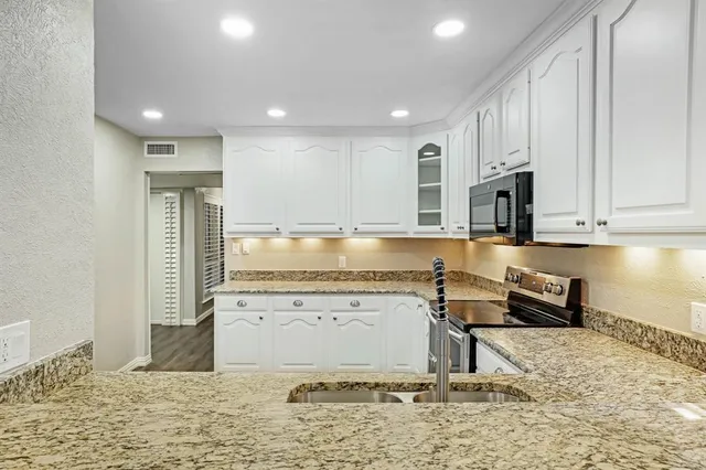 a kitchen with stainless steel appliances granite countertop a stove a sink and a microwave