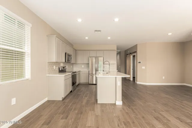 a kitchen with stainless steel appliances a white cabinets and wooden floor