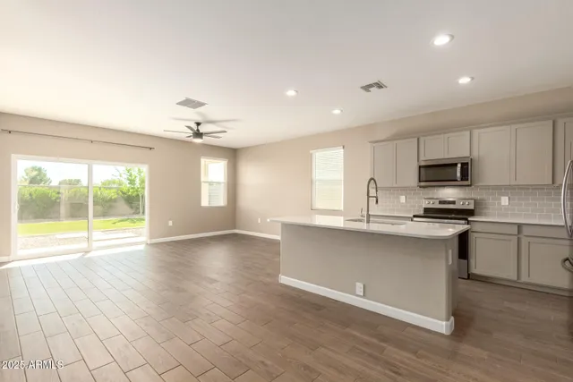 a open kitchen with granite countertop a stove top oven a sink dishwasher and white cabinets with wooden floor