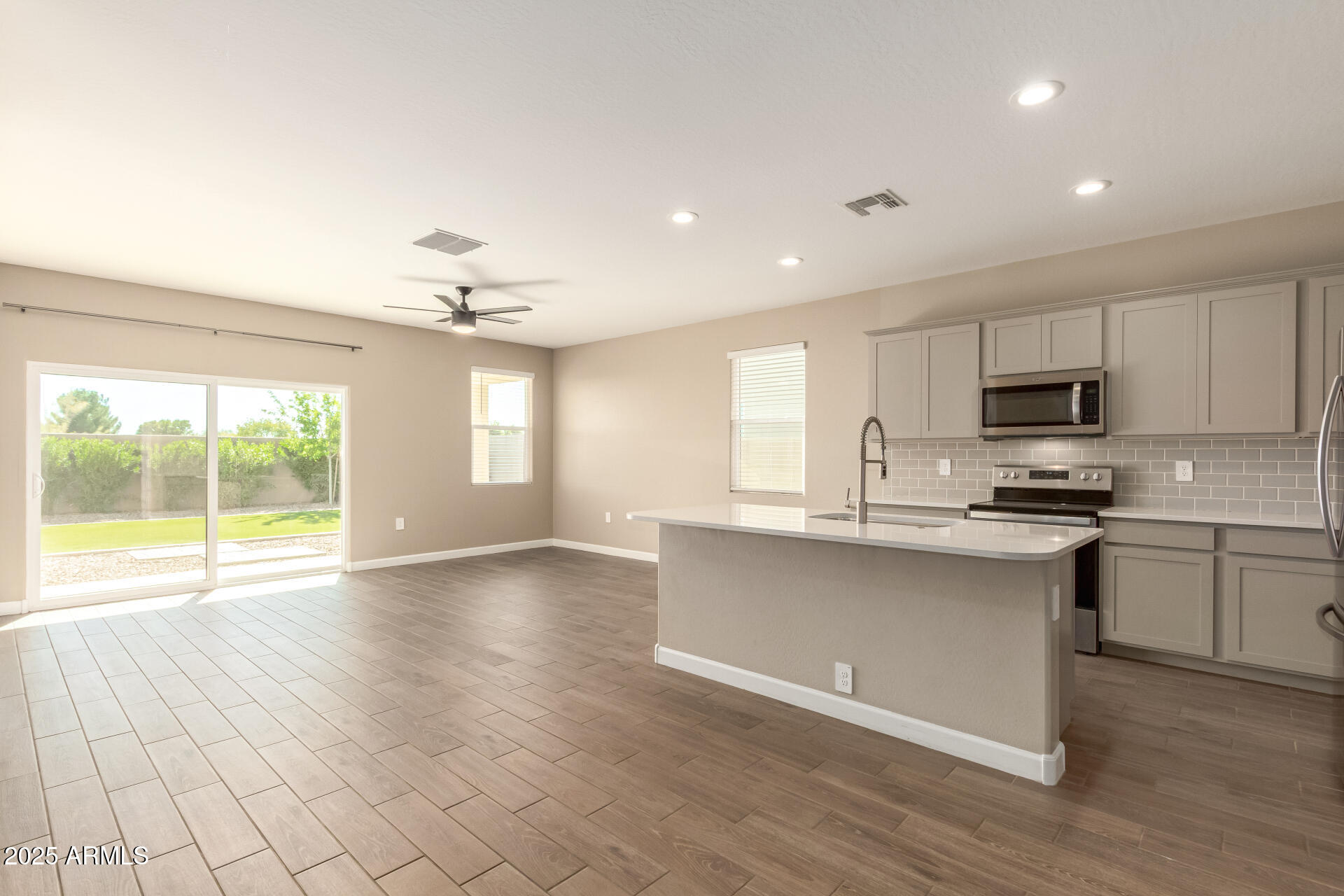1357 East Chillingham Road San Tan Valley, AZ 85143 - Photo 9 of 32 a open kitchen with granite countertop a stove top oven a sink dishwasher and white cabinets with wooden floor